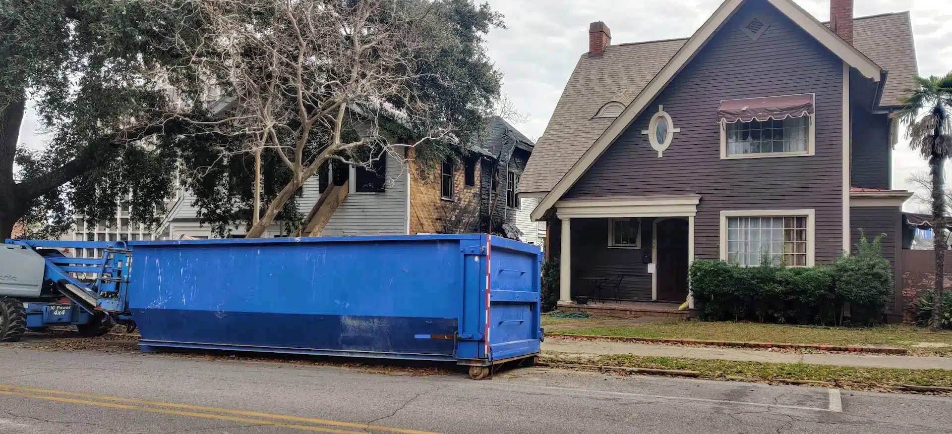 Blue roll-off dumpster in front of a residential home