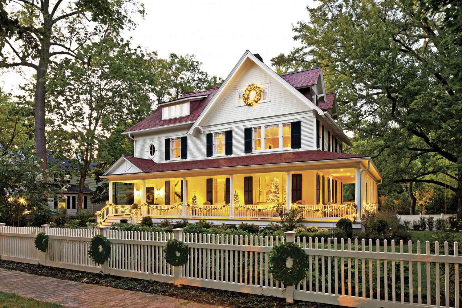 Beautiful outdoor picture of a white farmhouse decorated for the holidays