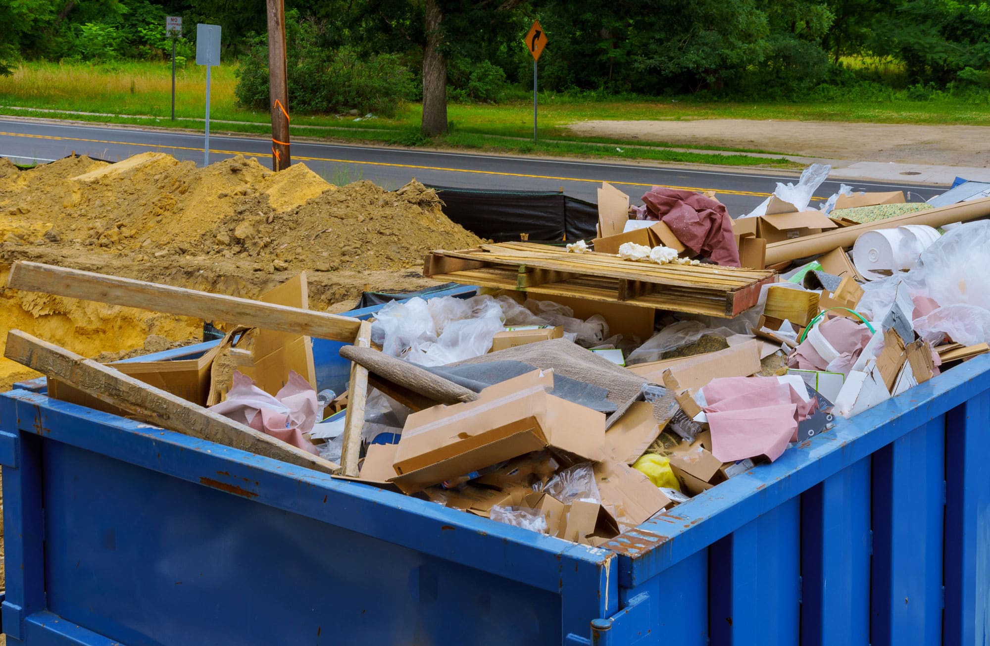 A construction roll off dumpster on a job site full of debris