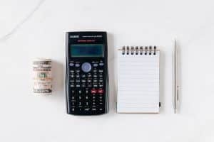 a calculator, pen, and money on a marble table