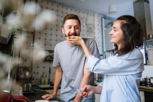 a man and woman in the kitchen eating cake
