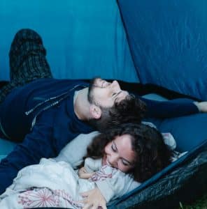 a man and woman laying in a tent