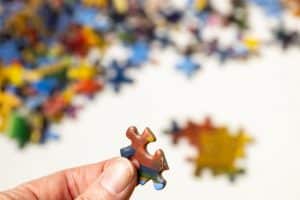 a person holding a puzzle piece in front of a white background