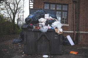 a trash can with garbage in front of a brick building