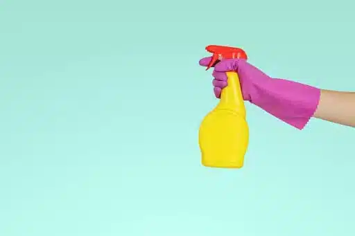 a hand holding a yellow spray bottle