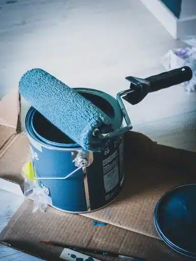 a paint roller and paint brush on a cardboard box