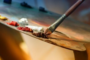 a person is painting with a palette and paint