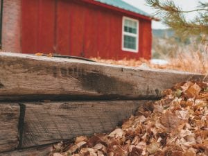 a red barn with leaves on the ground