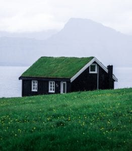 a small house with a green roof on a hill