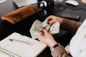 woman holding money at desk