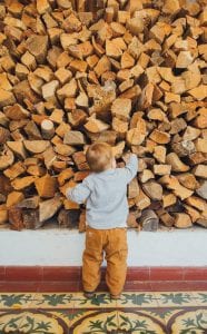 a child is standing in front of a pile of wood