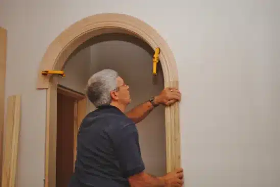 picture of a homeowner installing a piece of wooden archway trim
