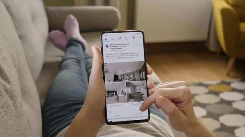 Person relaxing on a sofa while scrolling through Instagram home design posts on a smartphone.